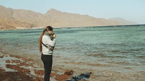 Woman is drinking coffee or tea on the beach with blue sea view, woman look in to horizon, rapid video, slow motion, 4k