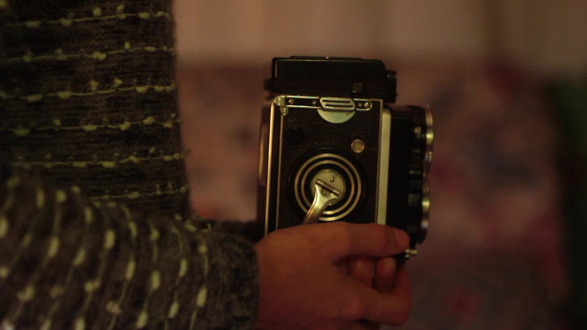 Film photography: winding the vintage Rolleiflex twin lens medium format camera and taking an analog picture.