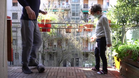 Europe, Italy , Milan - Father and children boy  five years at home during quarantine lockdown home due covid-19 Coronavirus outbreak - life stile in apartment - playing soccer football on the balcony