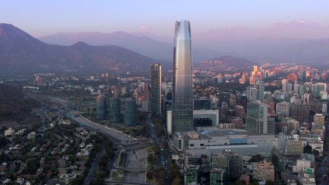 Aerial view of Santiago, the capital and largest city in Chile, showing landmark buildings in the financial district at sunset.