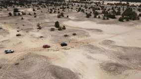 AERIAL. Several cars are driving along a sandy road. Drone aerial video. 