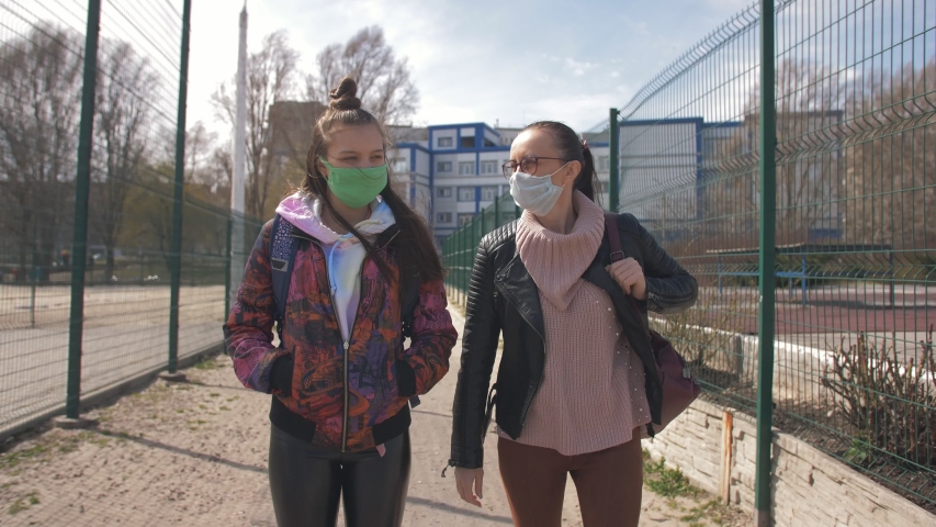 Mother and daughter a teenager walking down the street in protective masks.