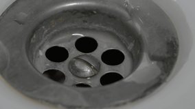 The drain sink with holes close-up into it drops a jet of water and then stops