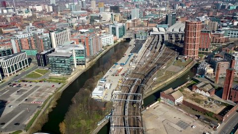 Aerial footage of the city of Leeds in West Yorkshire in the UK, showing the Leeds Train Station and train tracks along side the Leeds and Liverpool canal in the city centre