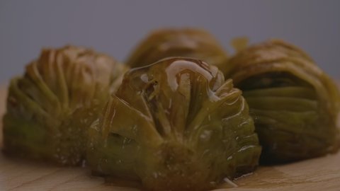 4 pieces of Turkish baklava in a wood plate shot in 4K slow motion. Turkish Hospitality with pistachio baklava