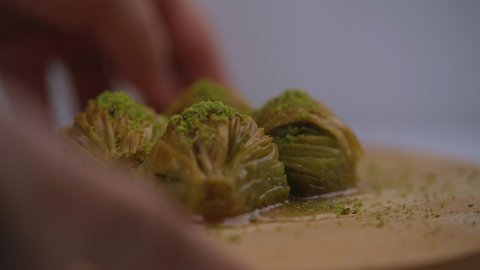 Delicious 4 pieces of tasty juicy Turkish Baklava with green pistachio nuts in a wooden plate