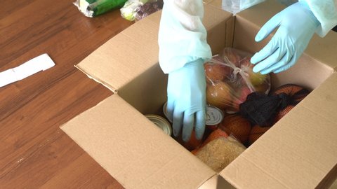 Takeaway and door delivery of goods. Food parcel, Volunteer, donation. Order picker in protective suit, hand gloves and mask. Coronavirus disease (COVID-19) pandemic. Online contactless food shopping
