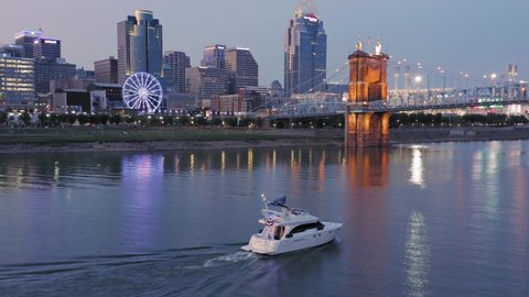 Aerial: Downtown Cincinnati and motorboat on the Ohio River at sunset. Ohio, USA. 21 September 2019 