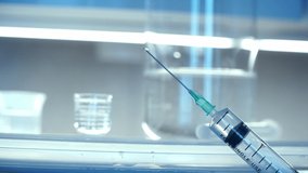 Close-up of syringe with medicine, on background of chemical flasks and beakers in laboratory. Concept of pharmaceutical research. - Powered by Shutterstock - Get 15% off with code: PIKWIZARD15