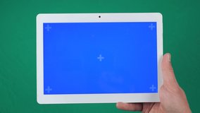 Horizontal tablet in the hand closeup isolated at green background. Tablet screen is blue chroma key, background with another chroma key green screen.