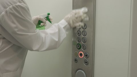 Woman using wet wipe and alcohol sanitizer spray to clean an elevator push button control panel. Disinfection, cleanliness and health care, Anti Coronavirus COVID-19