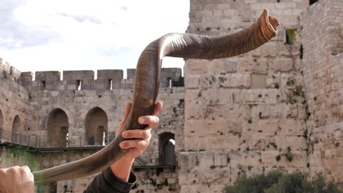 Jewish men blowing shofar in Jerusalem. Israel. The ancient walls of the old town, the City of David is on the background.