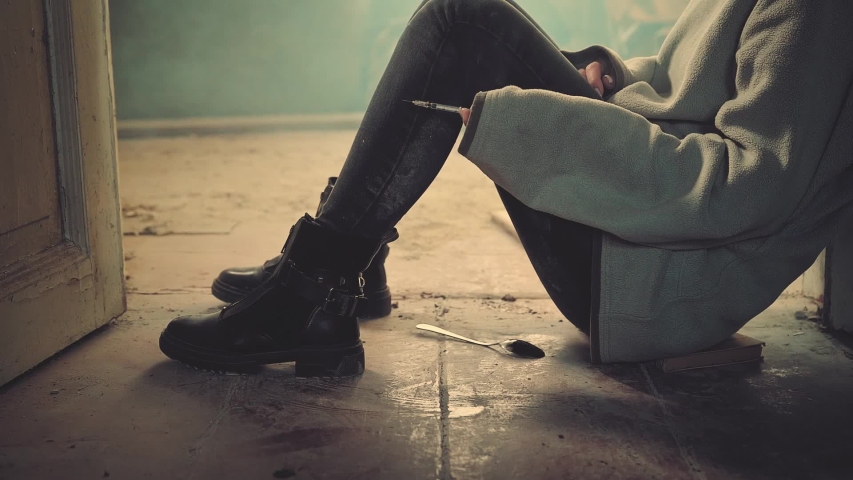 Addict woman with syringe in an abandoned house. Drug use, addiction, social degradation and self-destruction concept. Slow motion 