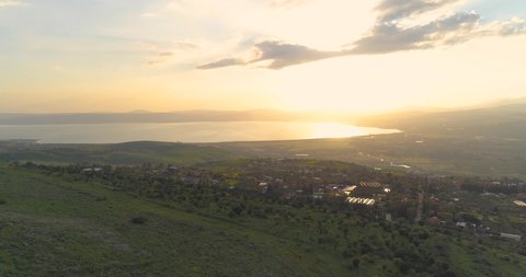 Aerial shot at sunset above Golan Heights and Taiberia in North of Israel. Open fields with orange green landscapes and mountains above Galilee sea or Kinnert at Jordan valley 