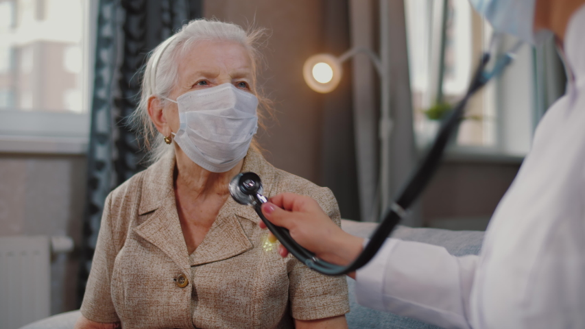 Female doctor use stethoscope to listen heart of elderly woman patient. Nurse home visit, checking health of old senior woman during coronavirus, covid-19 quarantine, self isolation Royalty-Free Stock Footage #1049767894