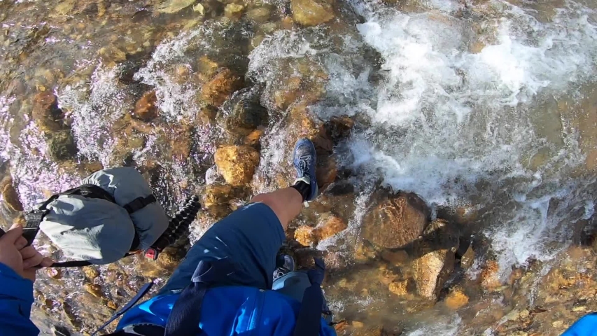 closeup of shoes crossing tiny river 