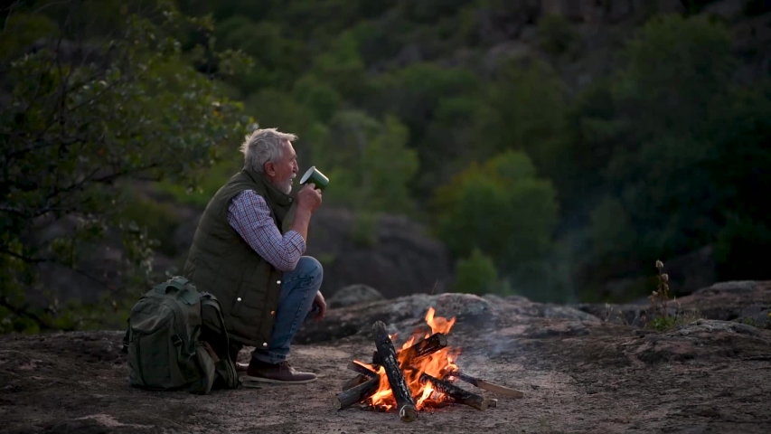 Senior man with gray hair, handsome tourist with backpack with a beard stay at the edge of the canyon and looking around. Senior man walking