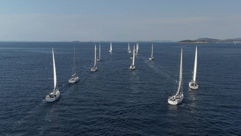 Ranks from yachts of participants of a regatta goes on a start point, is a sailing race at Croatia, reflection of sails on water, boat number aft boats