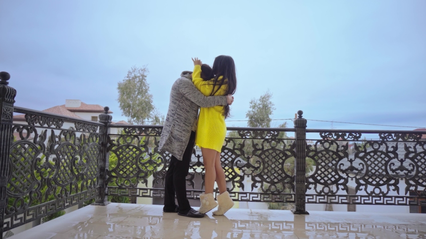 Young Couple In Love Standing And Tenderly Cuddling On balcony