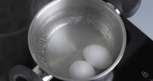 Two Raw White Chicken Eggs Hard Boiled In Stainless Pan In A Boiling Water. Healthy natural Protein Breakfast Cooking. Eggs Are Boiled. Chicken Eggs In Hot Water. Cinema 4K Video