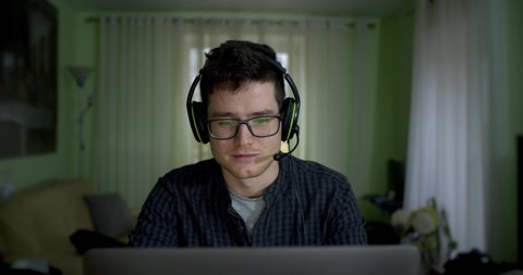 Working Remotely. Stay At Home! Young man, an office worker with glasses, works from home for technical support. talks to the client and is very focused on solving the problem Video de stock