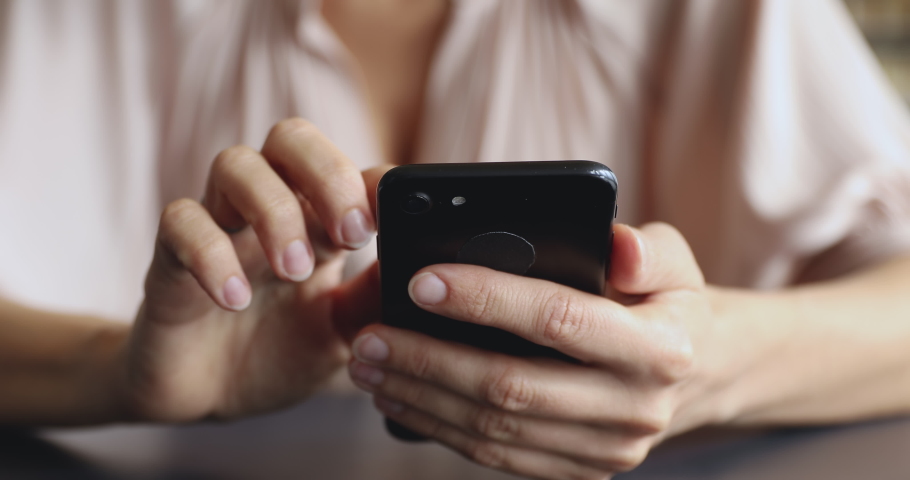 Close up female hands holding smartphone, using applications. Young woman communicating with friends in mobile messenger or social networks, web surfing information online, watching photos or video. Royalty-Free Stock Footage #1049816911