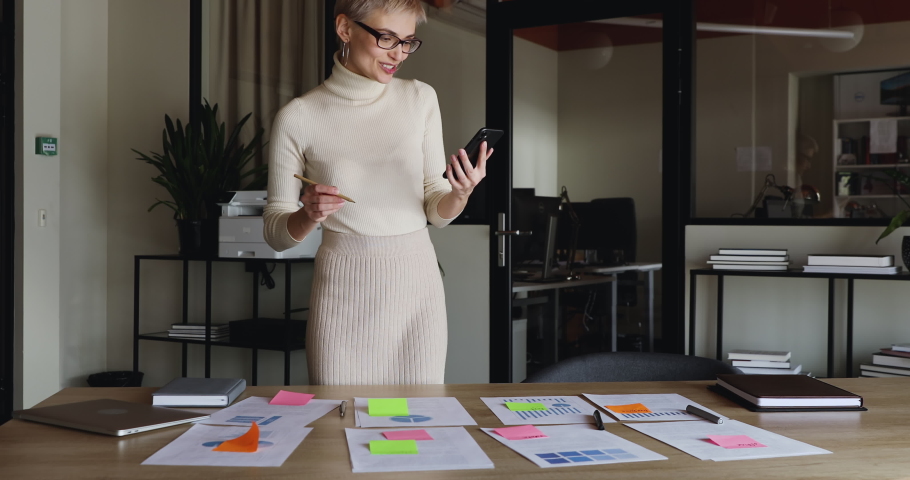 Young business woman designer holding smart phone communicating by video conference call planning work at distance corporate meeting. Remote worker talking with team in mobile videoconference chat. Royalty-Free Stock Footage #1049816998
