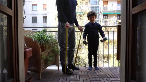Europe, Italy , Milan - children boy  five years with mask and father at home during quarantine due covid- 19 Coronavirus outbreak - life stile in apartment, do gymnastics and weights on the balcony
