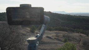 Taking video with mobile phone camera gimbal stabilizer, capture morning landscape time-lapse videos during sunrise.