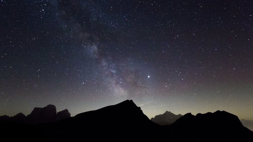 Milky Way Galaxy astronomy time lapse.  Timelapse stars moving above mountain valley in Dolomites Italy South Tyrol. Light pollution near horizon, science space universe presentation.