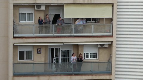 Huelva, Spain - April 5, 2020: Citizens staying at home and clapping everyday on balconies at 8 PM during the epidemic period of deadly coronavirus. People in quarantine in Spain