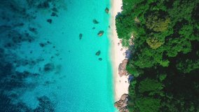 Aerial cinemagraph - seamless video loop of the beach of beautiful remote Island in South East Asia from above. The clear blue water is moving gently on the sandy beach and lush green jungle trees.