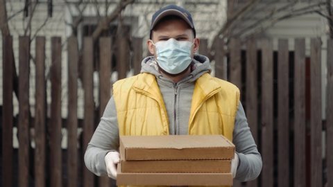 Delivery man holding cardboard boxes in medical rubber gloves and mask coronavirus pandemic quarantine home isolation. Fast and free pizza supermarket Delivery. Online shopping and Express e-commerce. : vidéo de stock