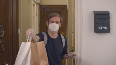 postman or delivery man carry small box deliver to customer at home. Man wearing mask prevent covid or coranavirus quarantine pandemic. Social distancing home isolation work concept.