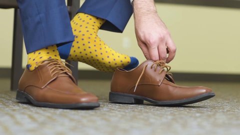 Man putting on Brown Dress Shoes with Yellow Socks
