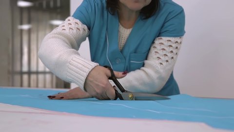 Cutting on the patterns of a medical gown. Cutting and sewing medical disposable clothing in blue color. Manufacture of clothing for doctors. Worker makes cutting medical clothes
