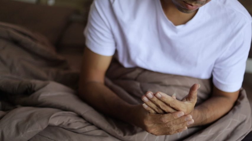 Young man wrist massaging painful hands and fingers on the bed slow motion, Young Asian Man suffering from pain in hand wrist , Health and pain concept