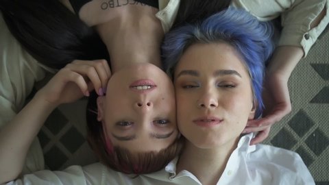 portrait of two teenager girls lying and looking at camera. Spbd gay lesbian friends feeling relaxed and chilling. concept tolerance, lgbt, enjoyment. woman teens bonding together. top view