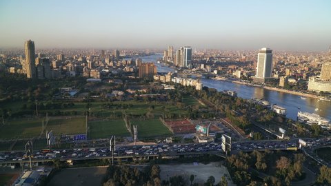 CAIRO, EGYPT - CIRCA 2020: Cairo city skyline. Aerial view of river Nile and the 6th October Bridge at sunset. Panning right.