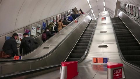 London Underground, UK -  January 2020: Escalators moving up and down staircase. Crowd of people moving on it.