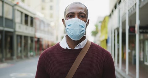 Portrait of an African American man out and about in the city streets during the day, wearing a face mask against air pollution and covid19 coronavirus.