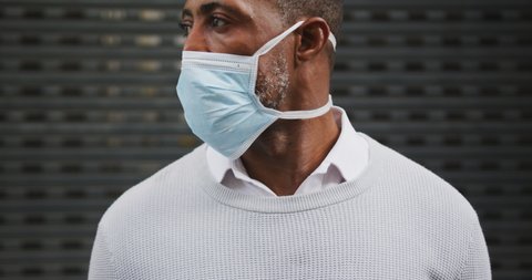 Portrait of an African American man out and about in the city streets during the day, wearing a face mask against air pollution and covid19 coronavirus, looking straight into a camera.