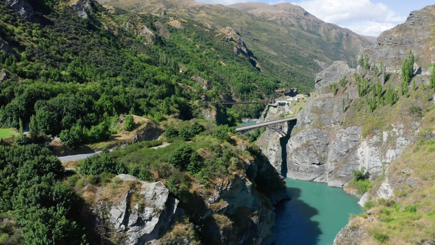 Suspension Bridge and canyon with two kayak steaming down the river. Famous Commercial Bungee Jumping spot, called Kawarau Bridge, Queenstown, New Zealand Royalty-Free Stock Footage #1049868208