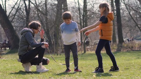 WROCLAW, POLAND - MAR 10, 2020: Happy family idyll have fun play in park with jump rope mother with two children boy and girl
