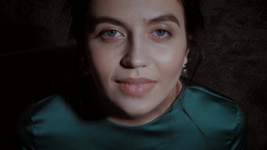 Beautiful woman tells poems. The model is dressed in a green dress in a romantic studio. A woman sits on a chair and talks to the camera.