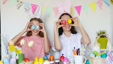 Mother and her little daughter have fun at Easter holiday. Family wearing bunny ears at home