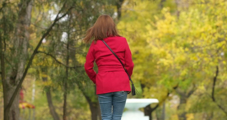 The girl rolls on the white kick scooter in the park near the dry fountain in the fall.