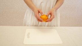 The girl cleans the orange tangerine. Tasty sweet fruit. 4k video.