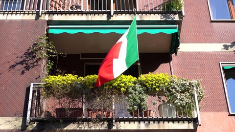 EUROPE, ITALY , MILAN  - Life in downtown during n-cov19 Coronavirus outbreak -  Flag of Italy hanging on the balcony of a house 