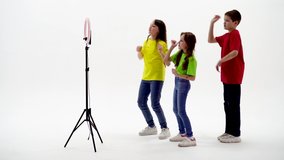 Two teen girls and a boy smiling and shoots a video. Selfies. The phone is mounted on a tripod and the ring lamp shines - Powered by Shutterstock - Get 15% off with code: PIKWIZARD15